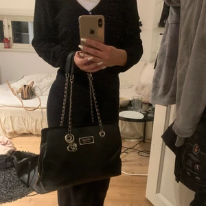 Svart Guess Väska - Hej, säljer min fina väska från guess då den inte kommer till användning längre. Köpt på Åhlens för ca ett år sen men är som ny! Inga slitningar eller repor vad jag upptäckt! Skriv för fler bilder!! Frakt tillkommer💕
