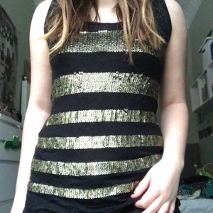 Coolt paljettlinne - Ett supercoolt linne med guld färgade paljettränder! Man känner paljetterna när man har på sig tröjan men tycker inte man störs av det. Stretchigt material så passar nog en storlek större också! Köparen står för frakten men möter annars upp på tc eller söder :)🌟