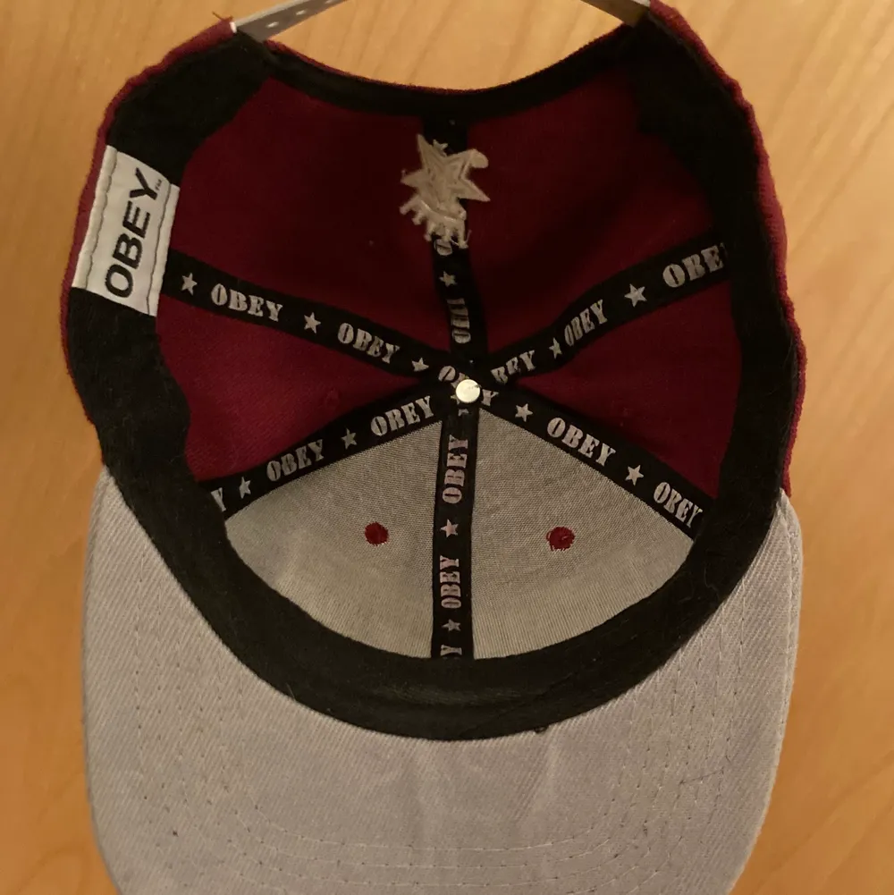 An Obey dark red and gray snap back baseball cap with the golden sticker still on. Gotten as a gift. Good condition.. Accessoarer.