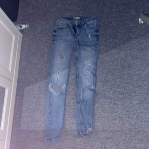 Ett par blåa jeans med hål på knäna å även hål i fickorna ibak. Storlek 26. Använda ganska mycket 