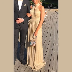 Guldig balklänning - Säljer nu min guldiga balklänning som är använd endast en gång. I nacken har den två långa band som man knyter till en rosett. Den är som finast i solljus då den glittrar ✨ Nypris 3200kr. Köparen står för frakten! 