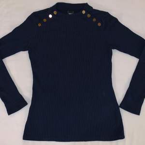 Dark blue sweater with gold buttons.