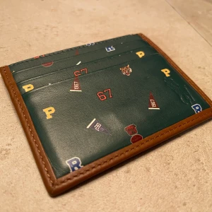 Polo Ralph Lauren korthållare - Jag säljer en Ralph Lauren Polo korthållare som köptes i NK för ett år sedan. Nypris var 899kr. Den är i mycket gott skick och väl använd, nu kommer jag dock sälja den för att jag har skaffat en annan korthållare. Boxen och trovärdighetscertifikat ingår. Jag kan skicka den om köparen står för frakt eller mötas upp i Stockholm.