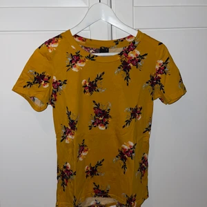 Senapsgul T-shirt blommig  - Säljer denna T-shirt jag köpte från ginatricot för några år sedan använt den 1 gång inte mer än det, den är jättefin och otroligt skön är senapsgul med fina blommor på, passar perfekt till sommaren