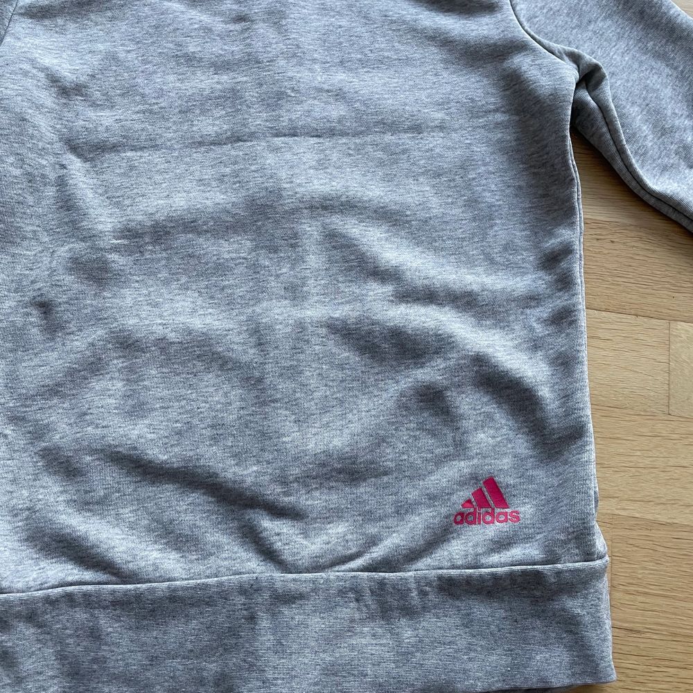 Jättefin Adidas zip up hoodie eller huvtröja i ljusgrå färg med rosa tryck☺️ Använd fåtal gånger så är i mycket bra skick och i storlek S dam. Den är ganska tunn med sköna fickor och perfekt att träna i eller ha till vardags:) Kontakta gärna vid frågor, fler bilder eller om du vill köpa💕 Frakt tillkommer på 62kr!. Huvtröjor & Träningströjor.