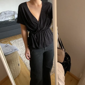Topp från HM - En omlott topp från HM i svart. Storlek S men passar ännu större med. Man kan knäppa ihop urringningen med en hake och annars är de knyt i sidan🥰