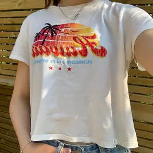 Vit T-shirt med  Hawaii-tryck från H&M i strl L, passar dock som S (jag har strl S i vanliga fall). Inget tryck på ryggen. Texten var ”sliten” när jag köpte den, så inget slitage. Aldrig använd, så nyskick. Kan köpas direkt för 90kr exkl frakt