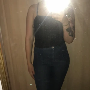 Svart stretchight linne med silverglitter - Svart linne med mycket stretchigt tyg och silverglitter i. Justerbara axelband, lite kortare än ett "vanligt" linne. Jätte skönt och tunnt tyg. använd 1 gång