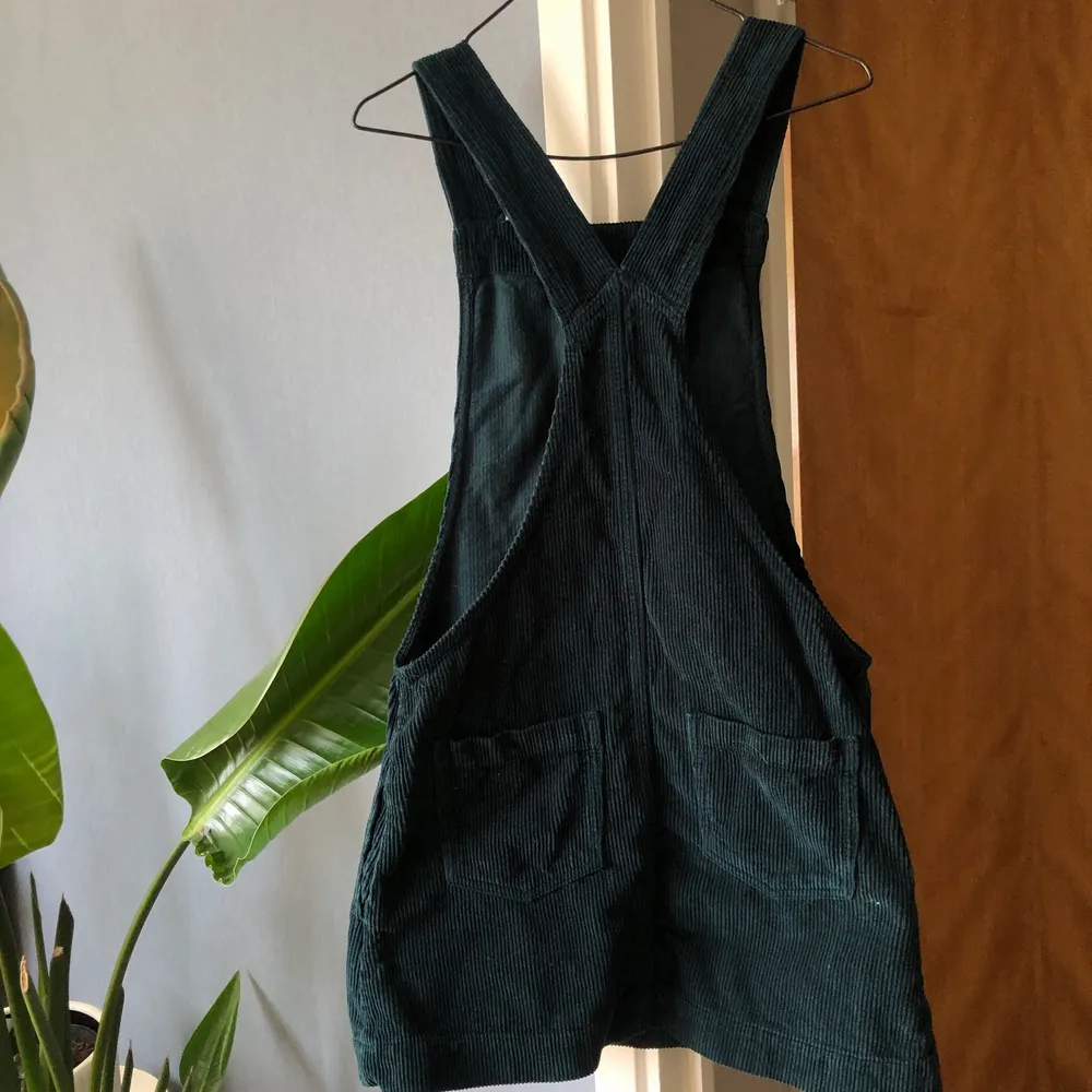 En mörkgrön hängselklänning från Urban Outfitters. Säljer pga inte min storlek. Det är manchestertyg så den är ribbad.. Klänningar.