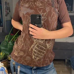 Brun T-shirt  - Säljer denna coola bruna t-shirt med guldiga tryck. Inte alls sliten och sitter jättefint. Köpt secondhand❤️⭐️passar s-m ❤️💯