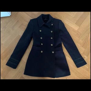 Zara kort Ullkappa - Jätte fin kort ullkappa från Zara i topp skick. Xs men ganska liten i storleken! Mörkblå med röda detaljer samt guldknappar. Kan hämtas i Göteborg eller fraktas för en extra slant. Nypris 999kr, mitt pris 350kr
