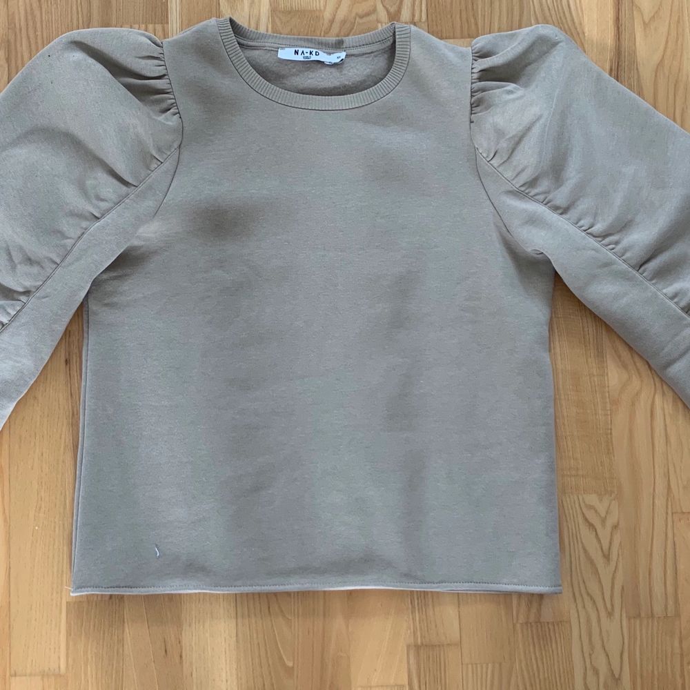 Sweatshirt från NA-KD, beige med lite ballongärm, rå kant nertill och vid i modellen, supersnygg! Knappt använd. Strl xs. . Tröjor & Koftor.