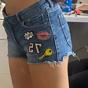 2000s Jeans Shorts - Jeans shorts med olika tryck på, typ 2000s vibes. Ganska stora i midjan så bälte kan behövas men annars skulle jag säga att de är XS 