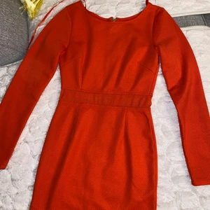 Klänning - Orange röd klänning som aldrig använts. Väldigt elastisk och har detaljer runt midjan