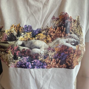 T-shirt med tryck. - T-shirt med tryck från NaKd. Inköpt för något år sedan och knappt använd. Den är ljusbeige, äggvit ish. Storlek XSS, men skulle snarare säga XS-S