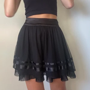 Svart Kjol  - En volangtjol som har 2 lager o silkes ditaljer! Har en dragkjedia på sidan för att stänga