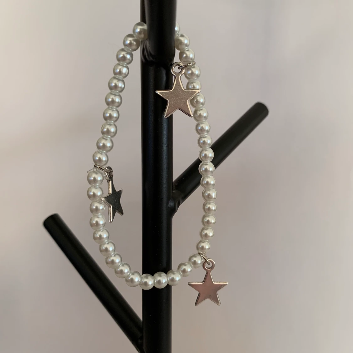 Vitt pärlarmband med silvriga stjärnberlocker