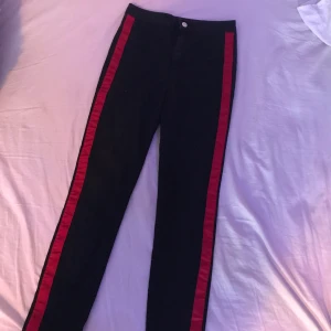 Jeans 36 - Tunna supersköna jeans med ett rött sträck längs benen. Inga fickor. Slutar vid foten.