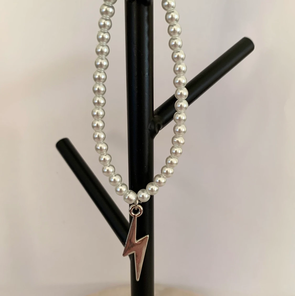 Vitt pärlarmband med silvrig blixtberlock 