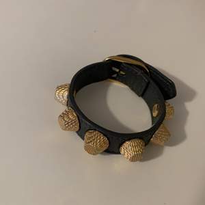Balenciaga armband i mörkgrå läder med guldnitar      Storlek S 