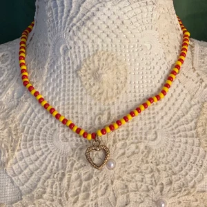 Pärlhalsband - Ett eget pärlat halsband med ett hjärta i mitten! Varannan gul pärla och varannan röd pärla. Ett silvrigt knäppe där bak. Halsbandet är 41 cm lång!❤️                                                 Hjärtat återanvände jag från ett gammalt halsband som gott sönder. Och pärlorna kommer också från ett gammalt halsband.                                                                                    Halsbandet är gjort av fiskelina och ska vara mycket stabilt! Skriv privat vid inträde. 