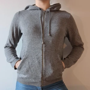 Mysig grå munkjacka med fickor - Mysig, grå, munkjacka från H&M Basic men silverknoppar på snörena till huvan/luvan, stl XS. Köparen står för frakten.