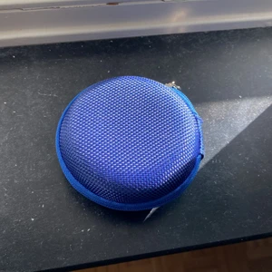 Inget märke  - Den är mörkblå. Det används till hörlurar skal och fler saker. Jag köpte den men insåg att det inte passade mina hörlurar och säljer den. Den är på bra skick