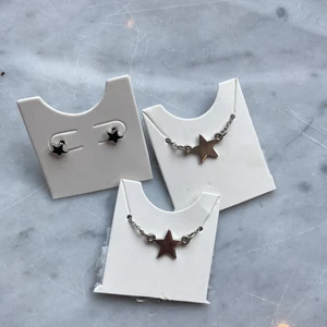 Silvriga stjärnsmycken - Populära och silvriga små örgängen med matchande  halsband och armband med en liten berlock. Oanvända och köpta på glitter💕köparen står för frakt!