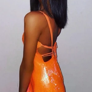 Paljettklänning - världens häftigaste miniklänning i orange men som får dig att verkligen synas! Den har justerbara band och kan spännas åt i midjan. Öppenryggad vilket är skitsnyggt och snygg snörning. Va huvudkaraktären och kööööp! Första bild lånad av hon ja köpte den av på plick. ja är str S, 175cm och den är ej för kort