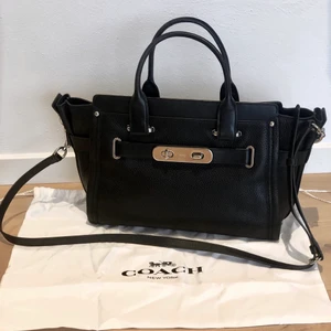 Coach väska - Säljer min svarta handväska från coach. Den är i fint skick men har bara inte fått användning för den på ett tag. Väskan kommer med en avtagbar axelrem samt dustbag, på insidan finns även ett fack. Den är 33 cm lång i nedkant och 22 cm hög. ✨❣️ Skriv vid intresse!🥰
