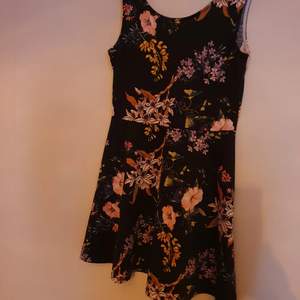 Säljer en svart klänning med blommigt mönster i storlek 40, jättehärlig att ha på sommaren.