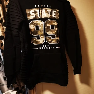 Svart hoodie - Svart hoodie med text i militär. Använd men fin i skick. Katt finns i hemmet. 