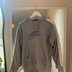 Nike hoodie - En grå nike hoodie med en vit ränd på ärmarna. Köparen står för frakten!