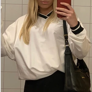 Vit tröja med svarta kanter - Väldigt unik o cool tröja köpt på Frank & Buster för 300kr. Den är ganska stor men går även att förminska. Tycker dock att tröjans charm är att den är stor o pösig :) använd några gånger men de märks ej.