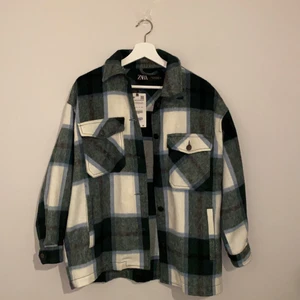 Rutig vårjacka från Zara st. XS - En fin vårjacka från zara som är i färgerna vit, grön, blå och grå. Jackan är aldrig använd. Jag är 1.59 lång och jackan går lite nedanför min rumpa.
