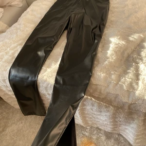 Skinbyxor med slit  - Ett par ganska bekväma svarta skinbyxor som blir lite wide vid botten där det också finns en slit. Aldrig använda.