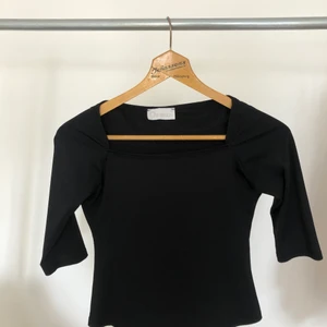 Svart tröja  - Svart tröja i glansigt material. Litet litet hål (se bild) framtill ned. 