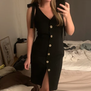Svart klänning - Svart klänning med button up. Knytes på axlar. Så fint flattering material med stretch. Passar allt från m till l beroende på hur tight man vill ha den.