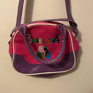 Barbapapa väska - Köpt second hand och verkar vara gammal därför har färgen försvunnit lite på trycket (se bild 2) men det är inget man tänker på då handtaget hänger över. Jättegullig i alla fall💕Frakten kostar 57kr. 