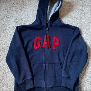 Gap zip hoodie  - Mörkblå gap hoodie med dragkedja med röda bokstäver. Den är använd och skicket är 7-8/10 och inga flaws. Det är 12-16 barn storlek och sitter som ungefär som en xs. Priset kan diskuteras 