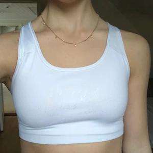Nike sporttopp strl. S - Vit sporttopp från Nike i strl. S. Inte vadderad. Nikeloggan är tryckt med glittrigt guld. Mycket bra skick! Gratis frakt.