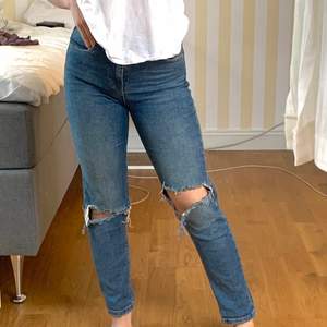 Blå högmidjade jeans från Gina Tricot i stlk 34 med hål. Jättesköna och stetchiga så de formar sig fint efter kroppen. Fraktar eller möts upp i gbg