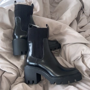 Högklackade boots med rafflad sula  - Högklackade boots med svart färg. Resår i sidorna med dragflik bak och fram. Tjock och rafflad sula. Aldrig använda endast testad. Nypris 559kr, frakt ingår 