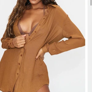 Skjorta  - Brun strand skjorta som även kan användas till vardagen. Super fin och går ihop med all bikini. Oversized, så går ihop med folk som bär S och M. Använd en gång!                                    