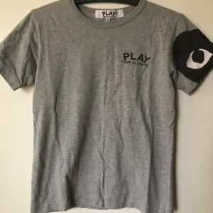 CDG Play / Comme Des Garçons Grey T-Shirt  Size small, fits like a regular size small.  Excellent condition, no flaws or damage.  DM if you need exact size measurements.   Buyer pays for all shipping costs. All items sent with tracking number.   No swaps, no trades, no offers. 
