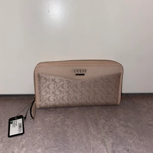 Plånbok/kuvertväska från Guess - Plånbok/kuvertväska från Guess i beige. Aldrig använd. Köptes för 650kr. Köpare står för ev . frakt. 