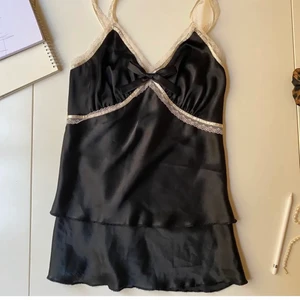 Sidenlinne med spets - Silkigt, sexigt och snyggt linne i nattlinne-inspirerad stil. Finns ingen nummerlapp på den men skulle säga XS-S! Har som en liten ”kjol” dvs två lager av tyg på botten. Fina och nätta spetsband samt rosett på bröstet. Supersnygg att ha bara som den är eller nedstoppad i jeans 👖 