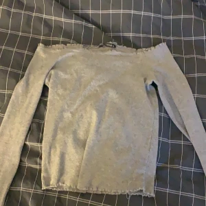 Offsholder  - Offsholder grå tröja med lite volanger runt magen 