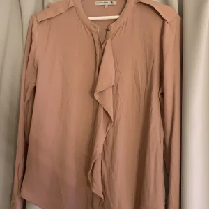 Rosa blus  - Rosa blus med volanger och knappar 