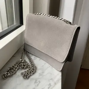 Handväska i ljusgrå mockaimitation med silvrig kedja, endast använd fåtal gånger. Från Pieces 💕 pris går att diskutera 